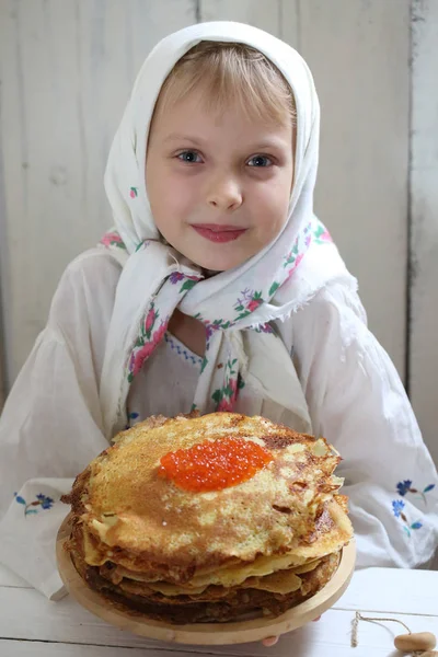 Ragazza seduta al tavolo delle vacanze. Frittelle con caviale rosso — Foto Stock