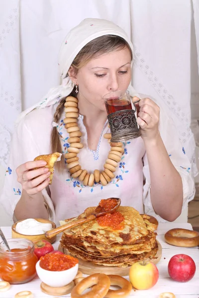 Het meisje aan de feestelijke tafel pannenkoeken eten en het drinken van thee — Stockfoto