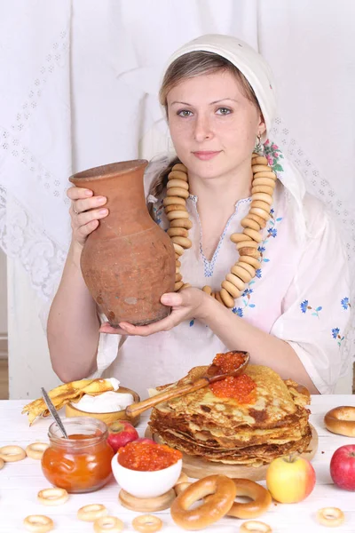 The girl at the festive table eating pancakes and drinking milk — Stock Photo, Image