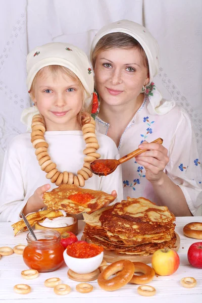 Дочка і мати їдять млинці з червоною ікрою. Сім'я в — стокове фото