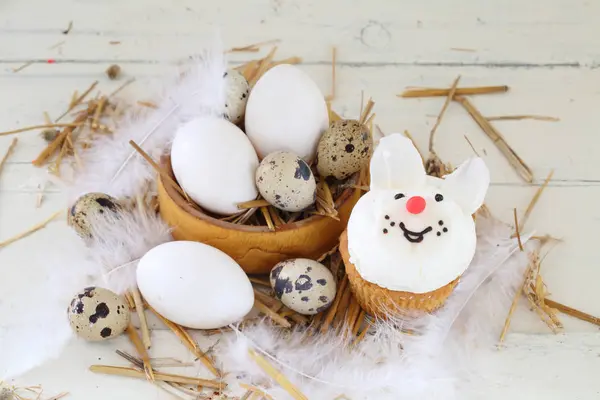 Quail and chicken eggs in a wooden bowl and willow branches — Stock Photo, Image