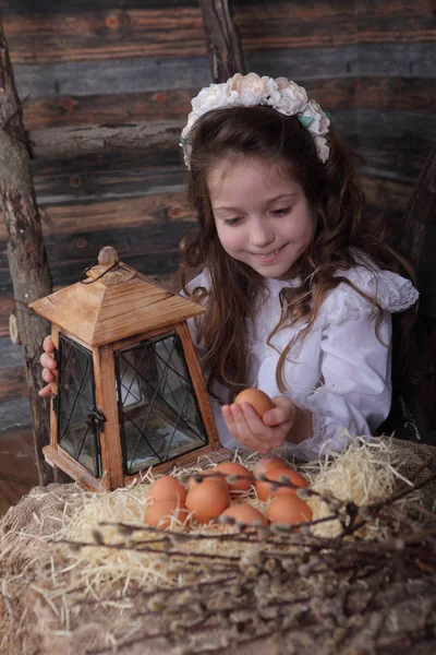 Девушка в венке и белом платье с яйцом в руках — стоковое фото