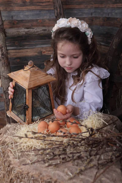 Девушка в венке держит яйцо в руках — стоковое фото