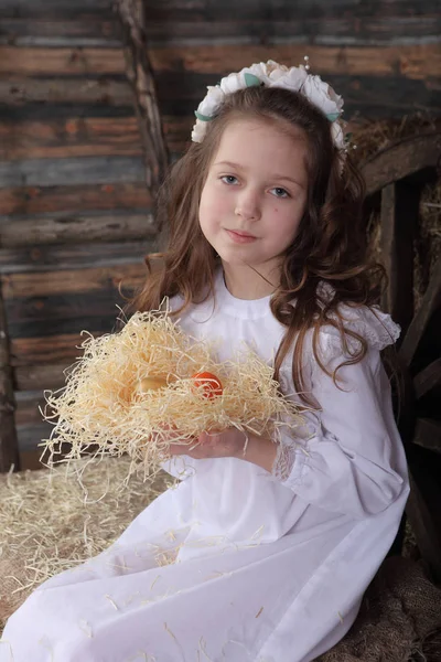 Menina em uma grinalda segurando um ninho com ovos de Páscoa — Fotografia de Stock