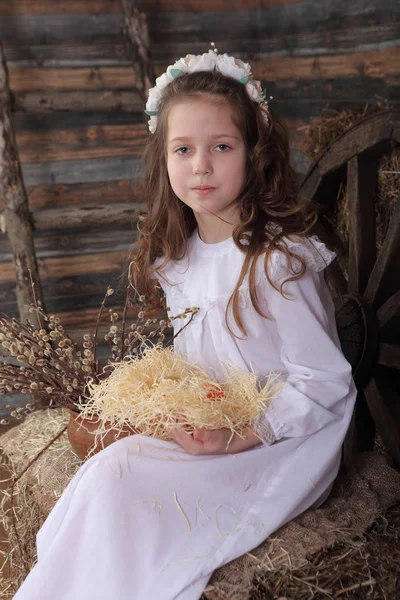 Menina em uma grinalda segurando um ninho com ovos de Páscoa — Fotografia de Stock