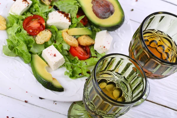 Vino bianco nel bicchiere e insalata con avocado — Foto Stock