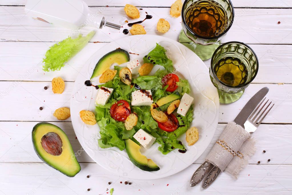 Salad with avocado , cheese and white wine in a transparent glas