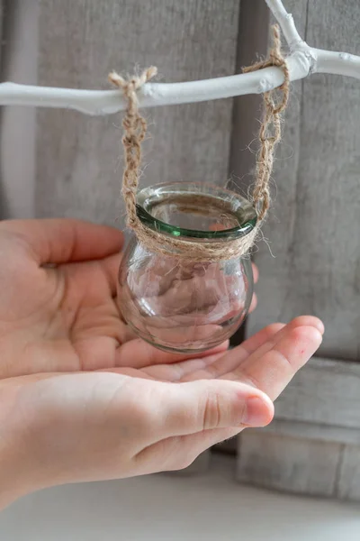 Acqua da bottiglia trasparente versata in un vaso di vetro appeso a una corda — Foto Stock