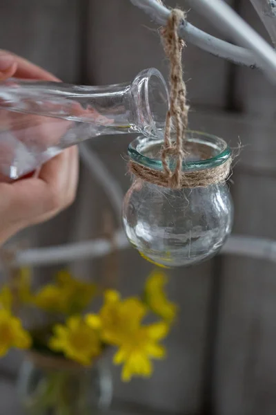 Acqua della mano del bambino dalla bottiglia trasparente versata in un vaso di vetro — Foto Stock