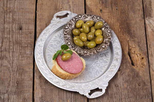 Сэндвич с сосисками и оливками на медном подносе — стоковое фото