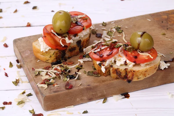Kanapka z pomidorem, białym serem i oliwkami na drewnianym stole — Zdjęcie stockowe