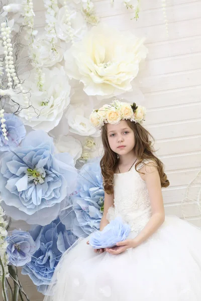 Ragazza in una ghirlanda e un vestito bianco che tiene un grande fiore — Foto Stock