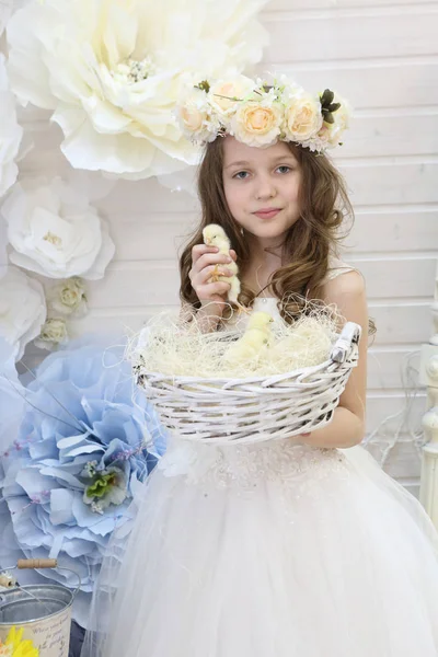 girl in a wreath and a white dress holds a woven basket with chi