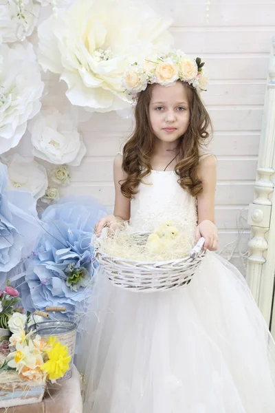 girl in a wreath and a white dress holds a woven basket with chi