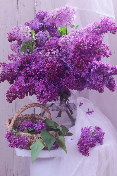 Du lilas. branche de lilas dans un bocal en verre et panier en osier — Photo