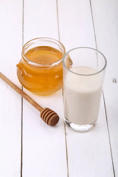 Burk honung och ett glas mjölk på ett träbord — Stockfoto
