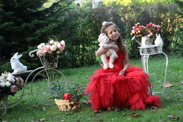 Meisje in de rode jurk houdt toy bear — Stockfoto