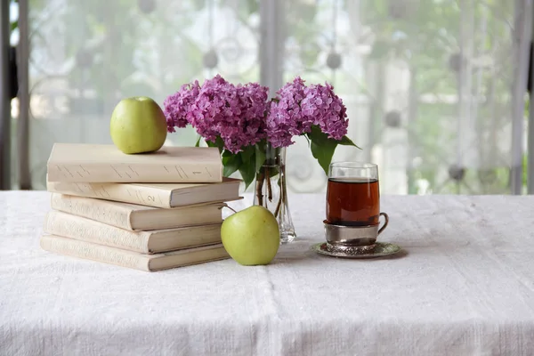 books and tea in a glass holder on the table near the bouquet