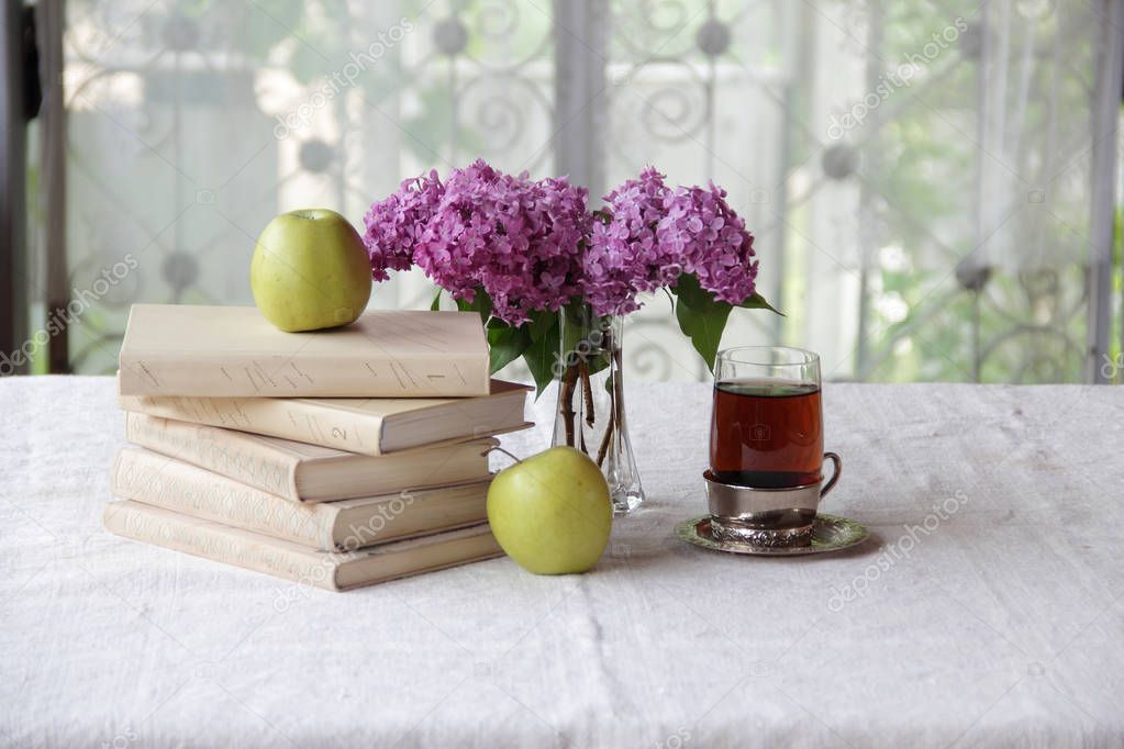 books and tea in a glass holder on the table near the bouquet