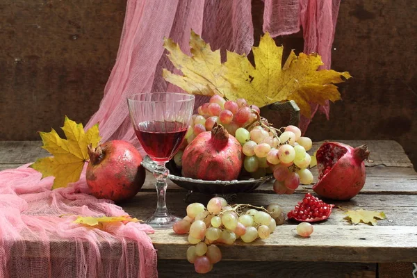 Natura morta con vino rosso, foglie autunnali, uva e melograno — Foto Stock