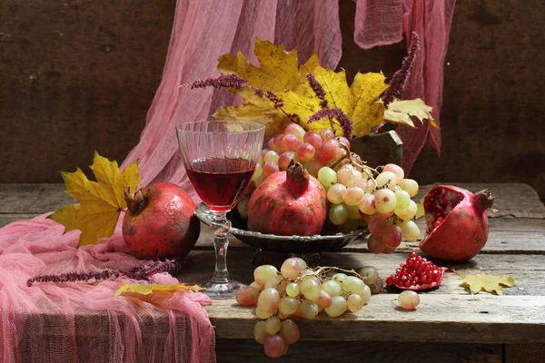 Vino rosso con frutta e un bouquet di foglie autunnali — Foto Stock