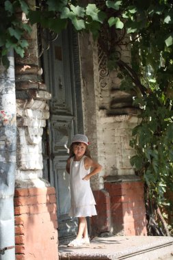 Beyaz elbiseli bir kapıyı önünde bir kız duruyor