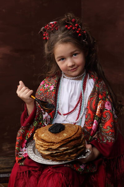 Девушка в русском костюме ест блинчики с черной икрой. Девушка в русском платье хранит блины с черной икрой

