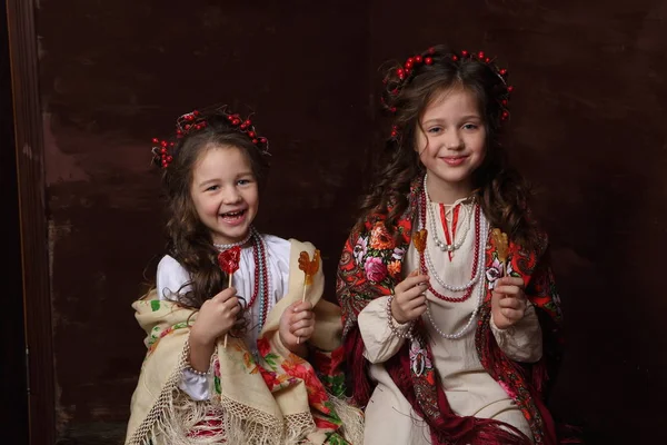 Girls in Russian dresses laugh and hold lollipops