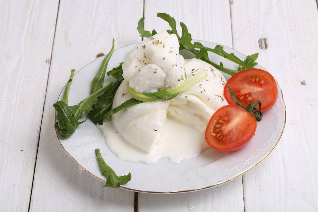 Cheese burrata with tomatoes on white wooden background