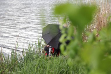 Nehirdeki balıkçılar şemsiye altında oltalarla