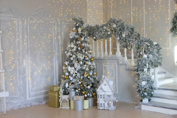 Beyaz merdivenlerin yanındaki Noel ağacının altında hediyeler