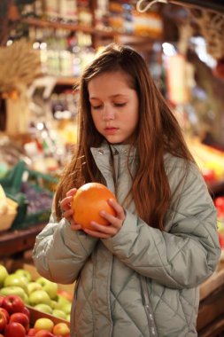 Tezgahın yanında greyfurt tutan bir kız var..