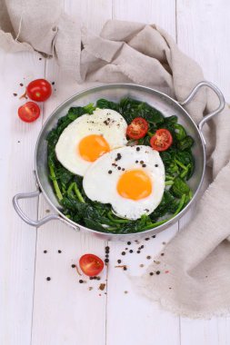 Tavada yumurta, domates ve yeşil ıspanak.