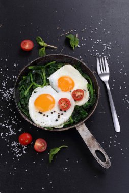 Tavada yumurta, domates ve yeşil ıspanak.