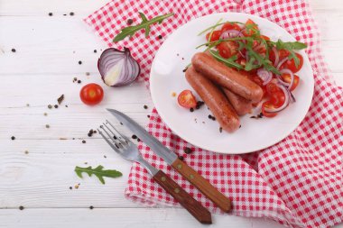 Sebzeli sosisler ve beyaz tabakta roka.