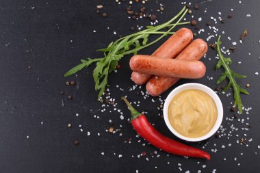 Siyah arka planda hardallı sosisler.