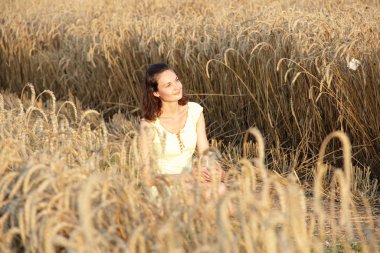 Kız bir kucak dolusu buğday kulağı tutuyor.