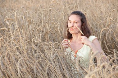 Buğday tarlasında kulaklarla oynayan bir kız
