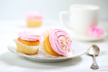 Kremalı kekler ve beyaz arka planda bir fincan kahve.