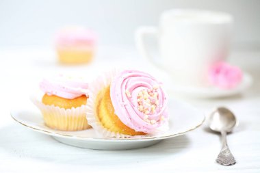 Kremalı kekler ve beyaz arka planda bir fincan kahve.