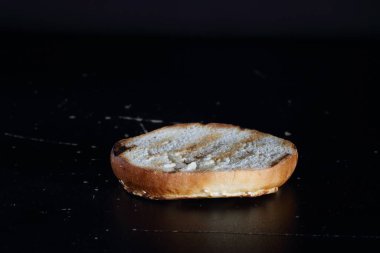Siyah arka planda hamburger ekmeği. Yarım burgerli çörek.