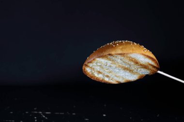 Siyah arka planda hamburgerler için susamlı kızarmış çörek.