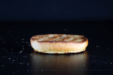 Siyah arka planda kızarmış hamburger ekmeği.