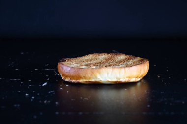 Siyah arka planda hamburger ekmeği. Yarım burgerli çörek.