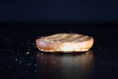 Siyah arka planda hamburger ekmeği. Yarım burgerli çörek.