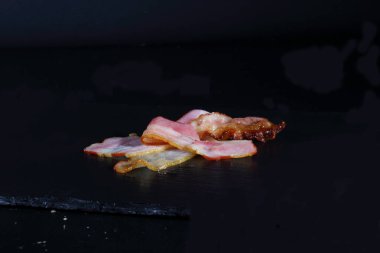 Siyah arka planda dilimlenmiş pastırma. Hamburger için pastırma.