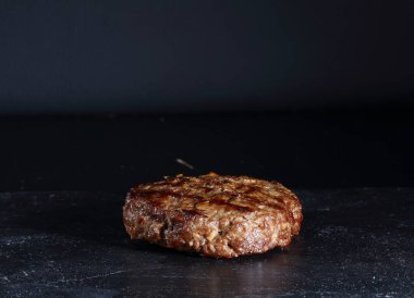 Siyah arka planda sığır burger pirzolası.