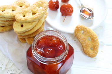 Beyaz ahşap arka planda süt ve elma reçelli kurabiyeler.