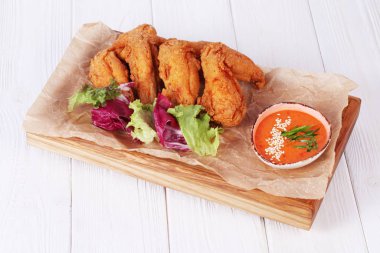 Beyaz tabakta baharatlı soslu kızarmış tavuk kanadı.