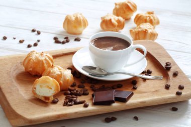 Profiterole with cream and a cup of coffee with chocolate